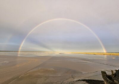 Arc-en-ciel vibrant au-dessus d'une plage calme.